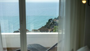 A view from a balcony overlooking the sea with a chair and a table.