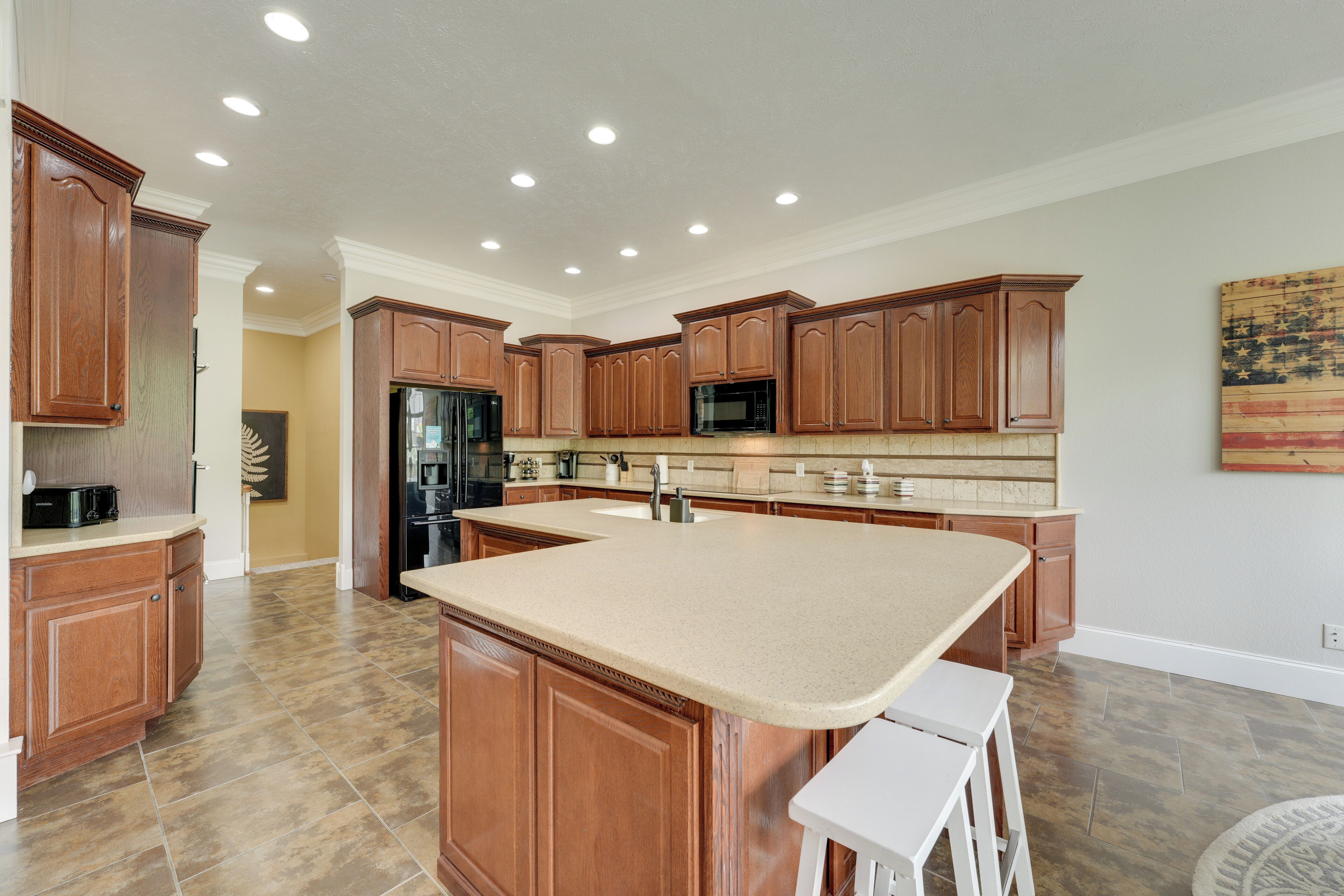 A spacious kitchen with wooden cabinets, a large island, and a refrigerator.