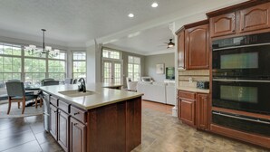 A spacious kitchen with a large island, wooden cabinets, and built-in appliances. - 4 Mi to Branson Landing: Huge Home w/ Game Room! (Branson)