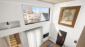 Eine moderne Wohnung mit Schlafzimmer im Loft-Stil, einem Essbereich und einem Wohnraum mit großem Fenster mit Blick auf die Stadt.