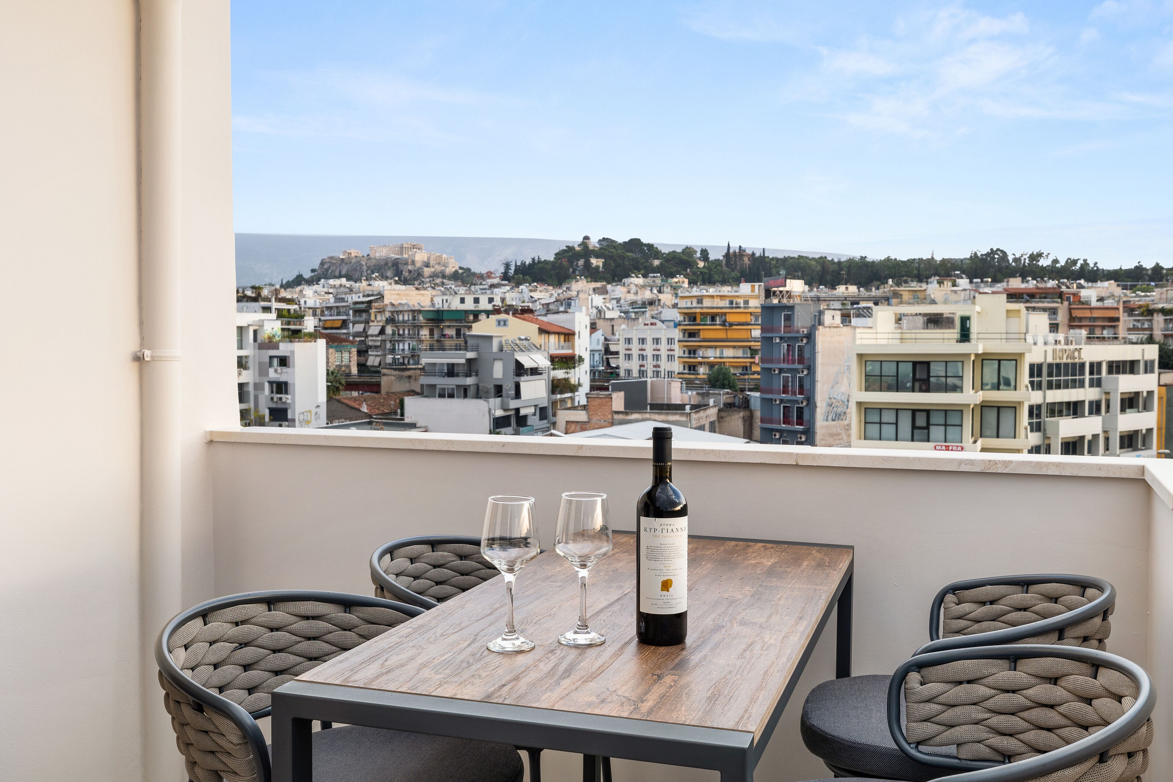 Un balcón con una mesa, dos sillas y una botella de vino.
