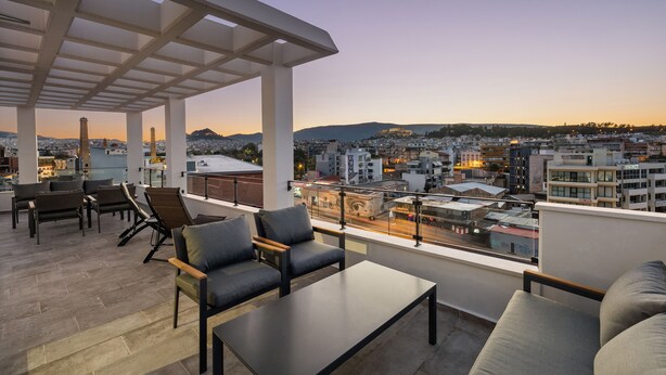 Eine Dachterrasse mit Sitzgelegenheiten und Blick auf die städtische Silhouette im Abenddämmerung.