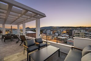 Terraza en la azotea con asientos y vistas de la ciudad al atardecer.