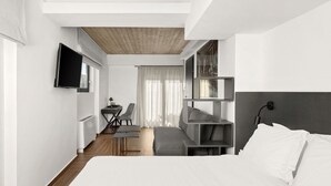 Ein modernes Hotelzimmer mit Bett, Schreibtisch, Stuhl, Fernseher und einem Fenster mit Vorhängen.