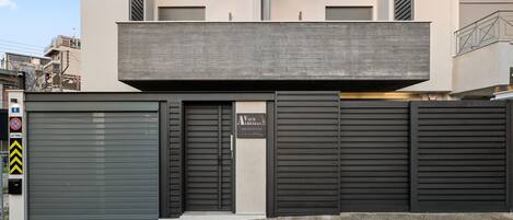 A modern building with a grey facade, large metal shutters, and a visible entrance.