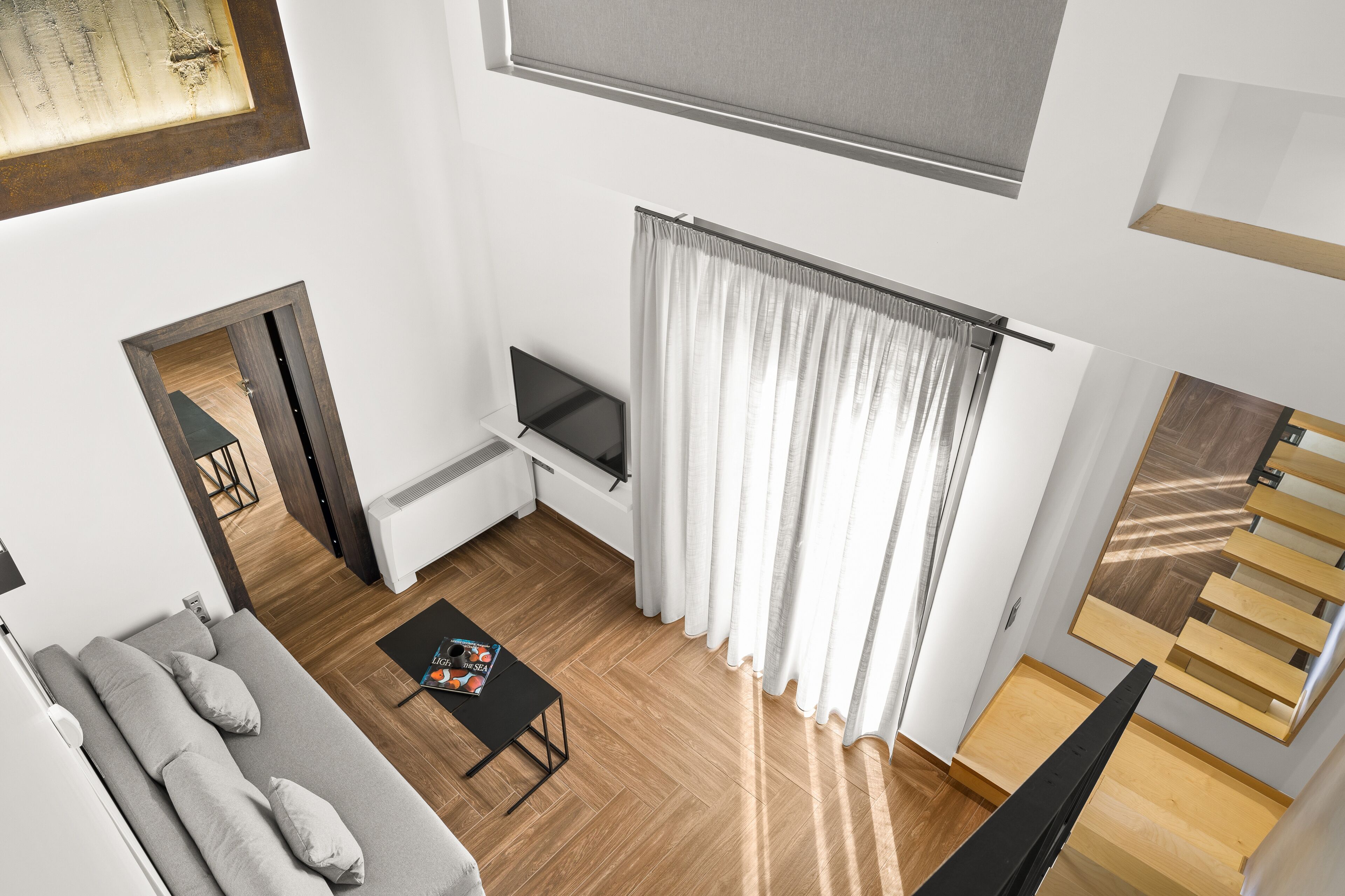 Un salon moderne avec un canapé, une table basse, un téléviseur et un escalier.