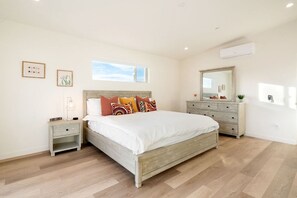 A bedroom with a large bed, bedside tables, a dresser, a mirror, and artwork on the walls. - Sun Oro - Hot Tub, BBQ, Fire Pit and Gameroom (Joshua Tree)