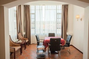 A dining area with a table set for four, surrounded by chairs, with a view through sheer curtains. - Antai Hotel (Anning)