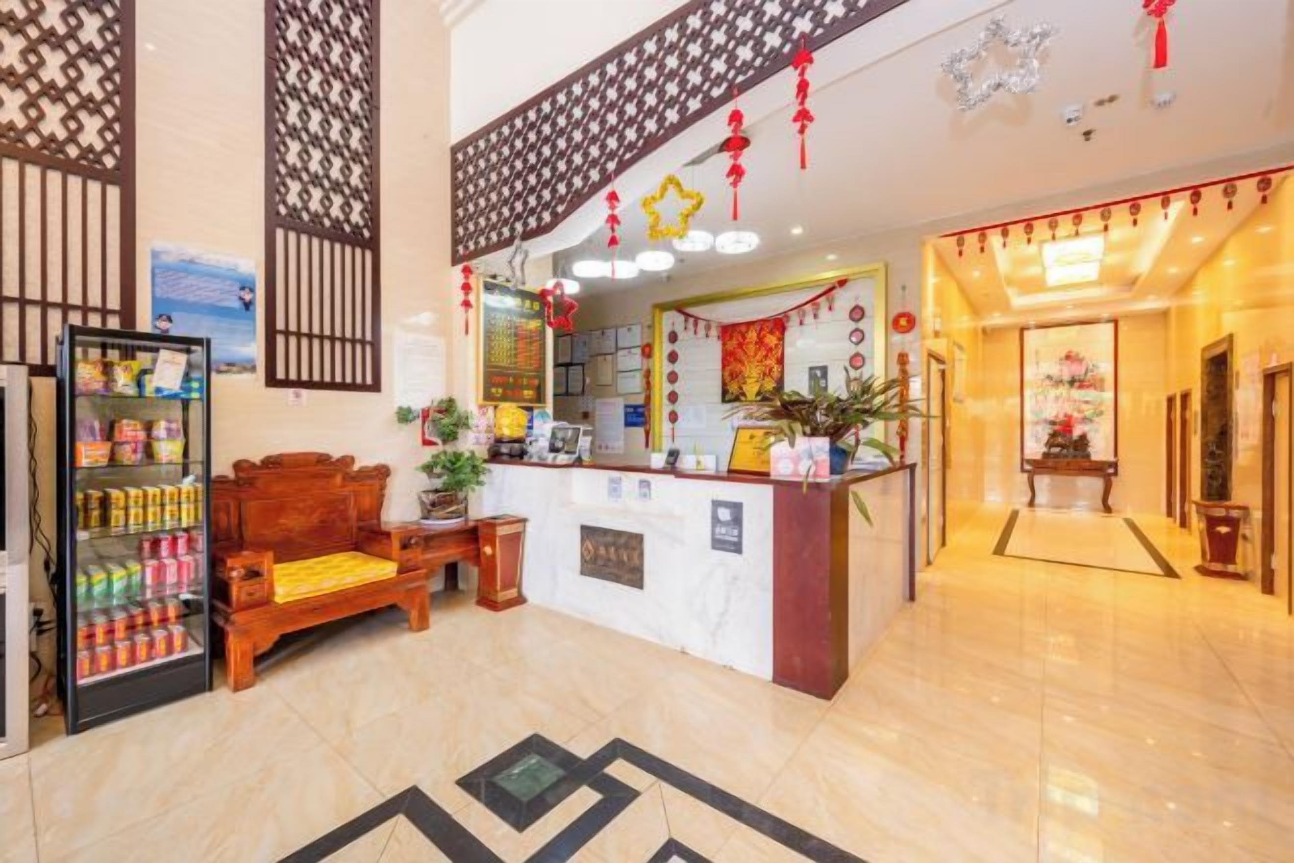 A hotel lobby with a reception desk, a seating area, and a decorative wall.