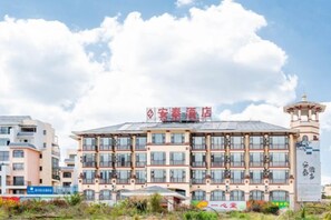 Un hotel de varios pisos con un letrero destacado, una estructura tipo torre a la derecha y cielo despejado.