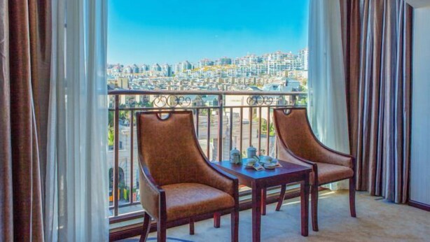 Un balcon avec deux chaises et une table, donnant sur un paysage urbain.