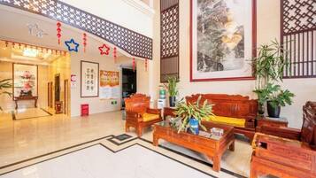 Un hall de hotel con mostrador de recepción, zona de estar y una obra de arte grande enmarcada en la pared.