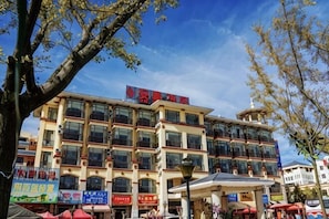 A multi-story hotel with a prominent red sign, multiple balconies, and a covered outdoor seating area. - Antai Hotel (Anning)