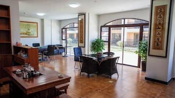 A spacious room with a dining table, chairs, a bookshelf, and large windows.