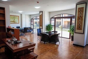 A spacious room with a dining table, chairs, a bookshelf, and large windows. - Antai Hotel (Anning)