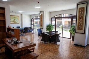 A spacious room with a dining table, chairs, a bookshelf, and large windows. - Antai Hotel (Anning)