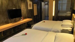 Habitación de hotel con dos camas, un televisor, una estantería de madera y una ventana.