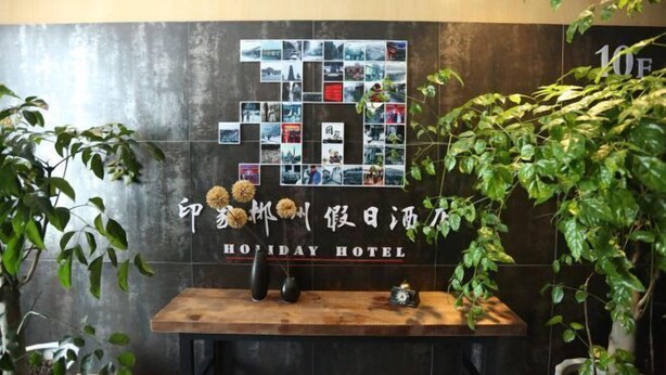 Un mostrador de recepción con un collage de fotos en la pared y un cartel que dice "Holiday Hotel".