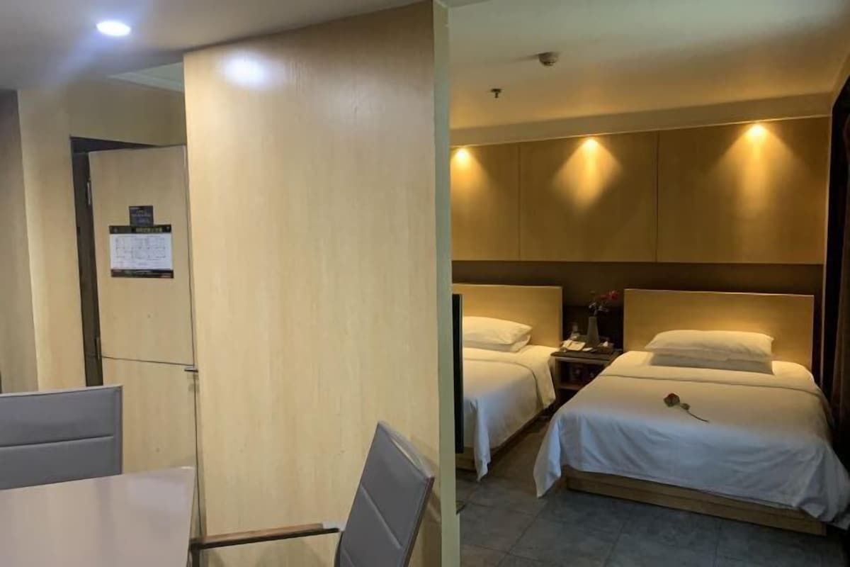 A hotel room with two beds, a desk, and a chair.