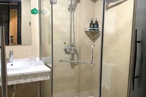 A modern bathroom with a glass-enclosed shower, a white sink, and a small shelf with toiletries. - Chenzhou Jiari Hotel (Chenzhou)