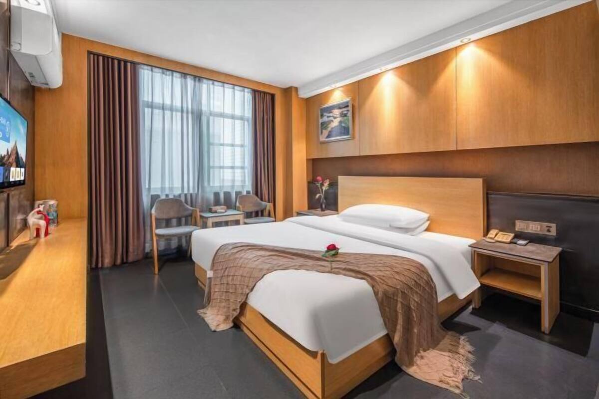 A modern hotel room with a large bed, a desk, a chair, and a television.