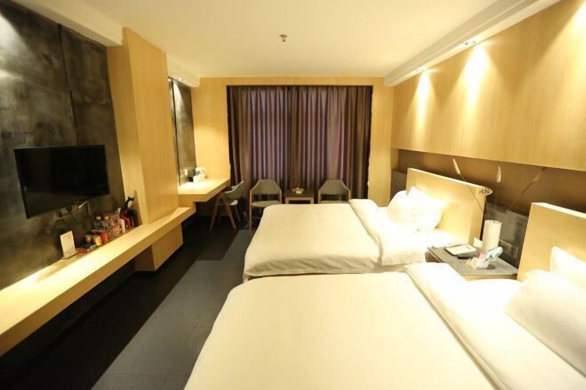 A hotel room with two beds, a desk, a TV, and a curtain.