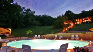 A swimming pool with lounge chairs and a stone wall.