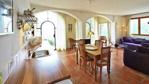 A spacious living area with a dining table, chairs, and a purple sofa.