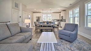 A modern living room with a sofa, armchair, and coffee table. A dining area with a table and chairs is visible in the background. - Kure Beach Townhome: Short Walk to the Beach! (Kure Beach)
