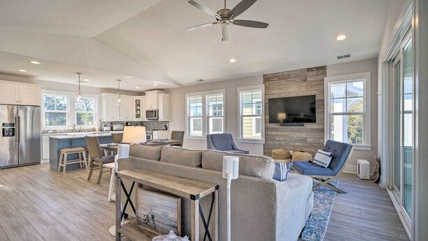 A spacious living area with a sofa, a coffee table, and a TV mounted on the wall. - Kure Beach Townhome: Short Walk to the Beach! (Kure Beach)
