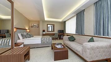 A modern hotel room with a bed, sofa, and a TV.