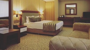 A hotel room with a large bed, a desk, a chair, a television, and a mirror. - Royal Sweet Hotel (Ankara)