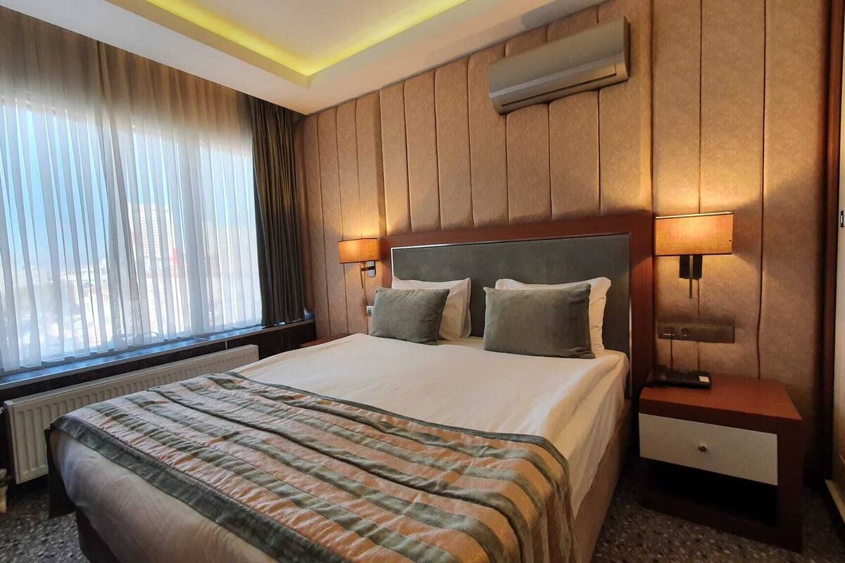 A hotel room with a large bed, two bedside tables, a desk, and a chair.