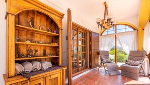Un meuble en bois avec des étagères, une porte en verre et une chaise avec un coussin.