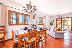 Uma sala de jantar com uma mesa de madeira, cadeiras e um lustre.