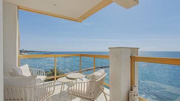 Ein Balkon mit weißer Möbel, Blick auf das Meer und einem klaren Himmel.