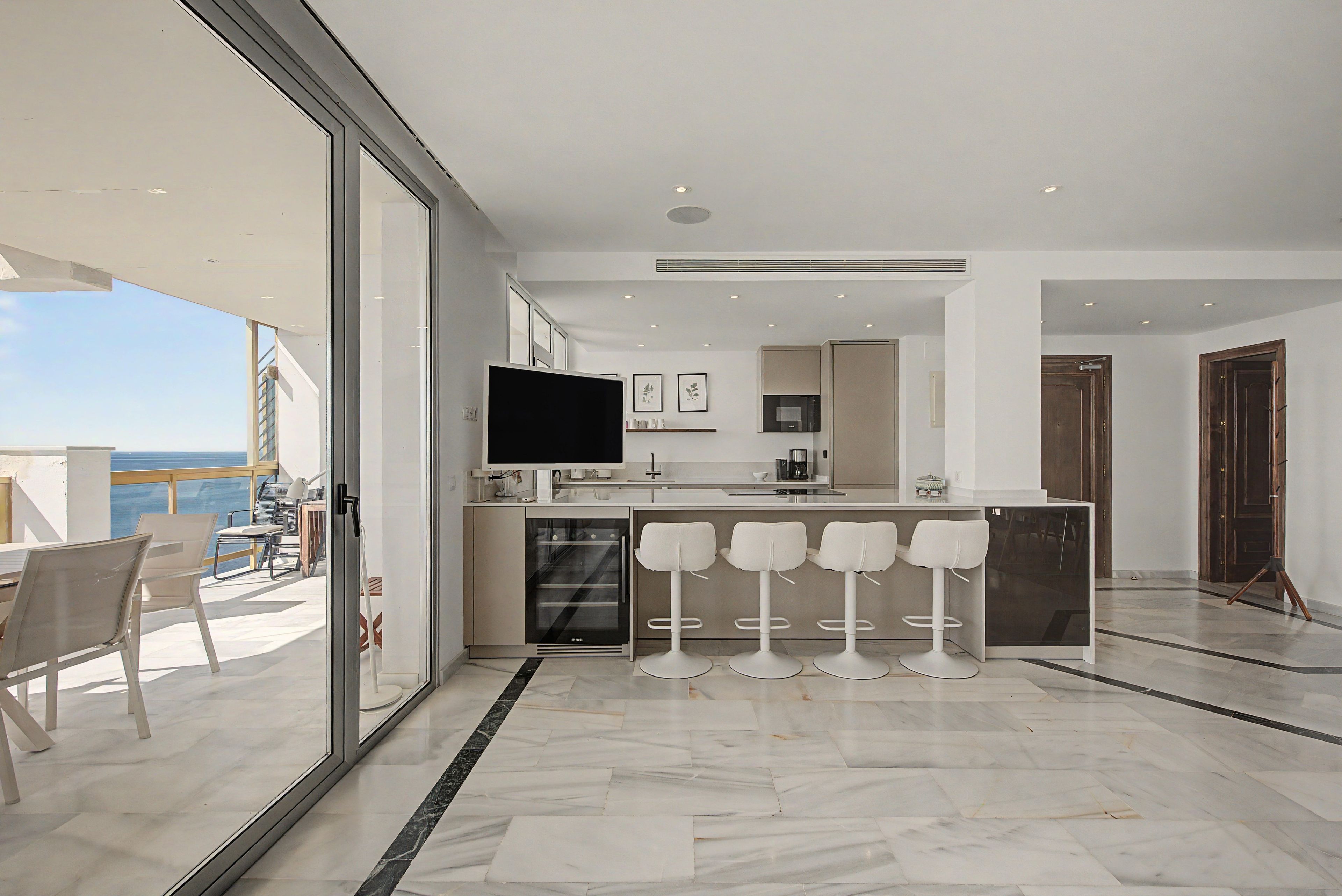 A modern kitchen with a large island, bar stools, and a television.