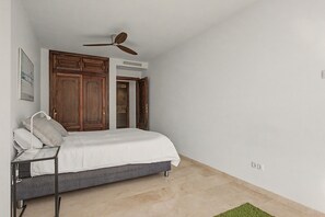 A bedroom with a bed, a ceiling fan, a wooden wardrobe, and a bathroom door. - Unique beachfront apartment with spectacular sea views, pool, Wi-Fi, and terrace (Marbella)