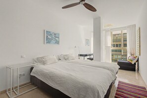 A bedroom with two beds, a ceiling fan, a desk, and a window with curtains. - Unique beachfront apartment with spectacular sea views, pool, Wi-Fi, and terrace (Marbella)