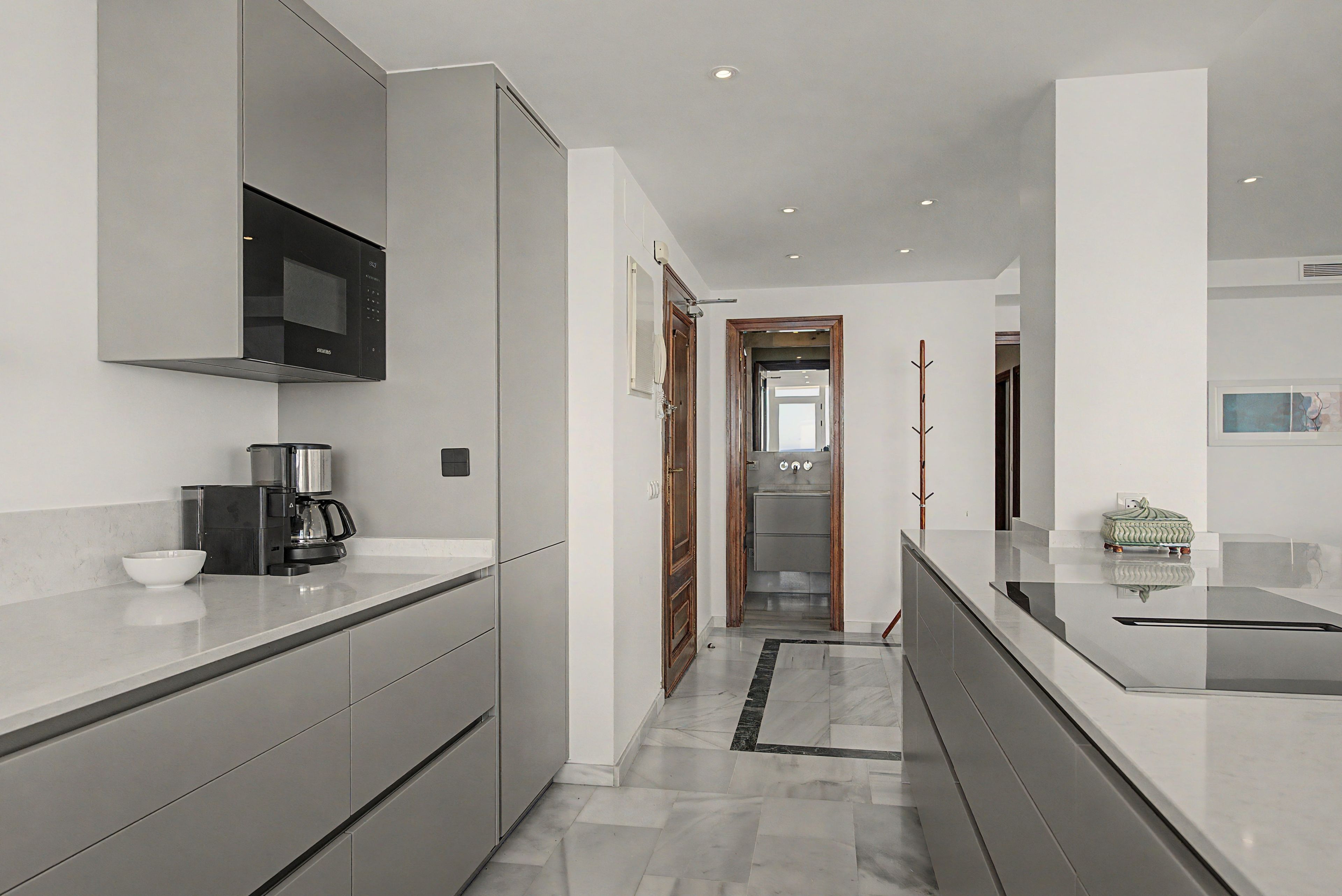 A modern kitchen with a built-in microwave, coffee maker, and a sleek countertop.