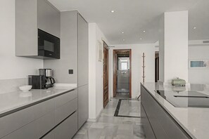 A modern kitchen with a built-in microwave, coffee maker, and a sleek countertop. - Unique beachfront apartment with spectacular sea views, pool, Wi-Fi, and terrace (Marbella)