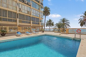 A pool area with lounge chairs, a lifebuoy, and a view of the ocean. - Unique beachfront apartment with spectacular sea views, pool, Wi-Fi, and terrace (Marbella)