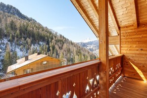 Un balcón de madera con vistas a una montaña y una cabaña.