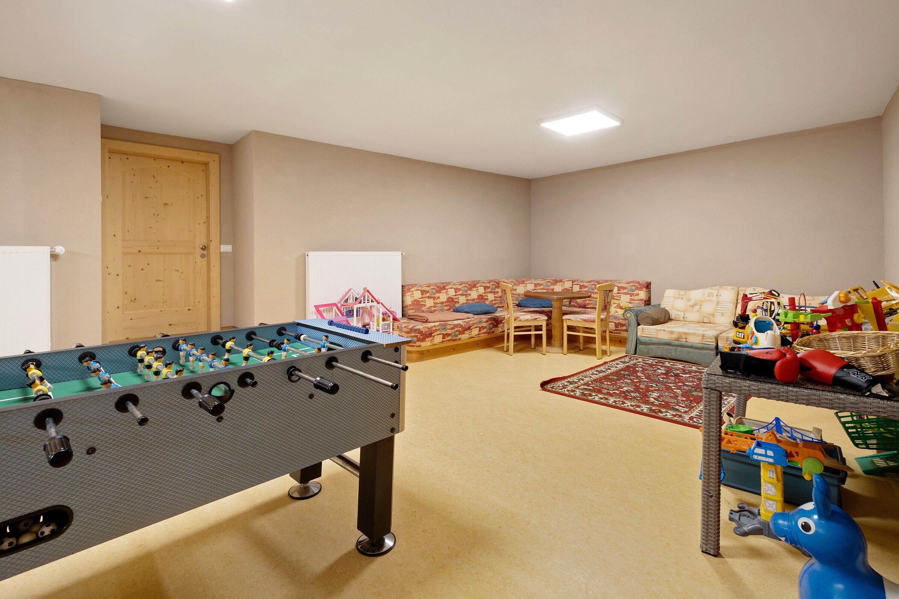 Une pièce comprenant une table de baby-foot, un canapé, une table basse et un petit espace de jeux avec des jouets.