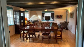 Un comedor con una mesa y sillas de madera, un televisor y un sofá al fondo.