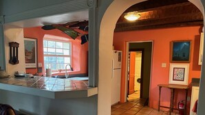 Una cocina con salpicadero de azulejos, una ventana y una puerta que da a un cuarto de lavado.