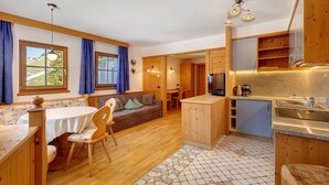 A compact kitchen with wooden cabinets, a built-in sink, and a dining area with a table and chairs.