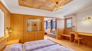 A wooden room with a bed, a desk, and a chair.
