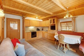 A cozy kitchen with wooden cabinets, a dining table, and a sofa.