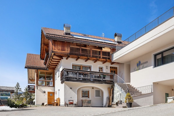 A two-story building with a wooden balcony, a staircase, and a sign indicating it's a residence.